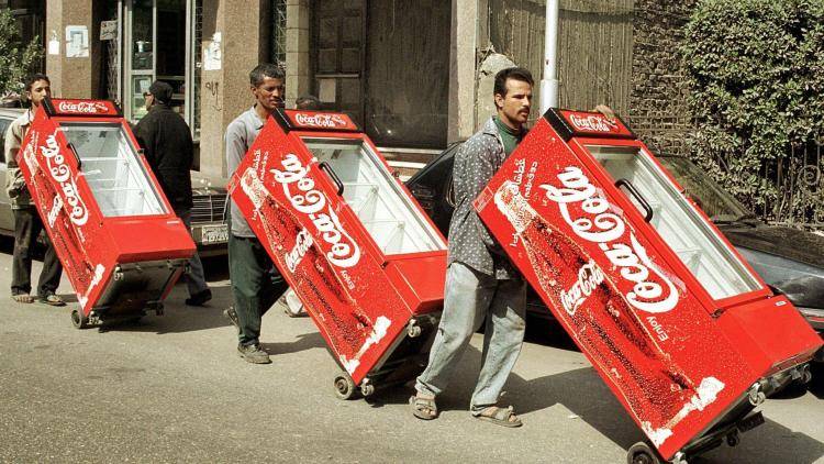 Three men wheel Coke fridges down a street in Cairo, 2000