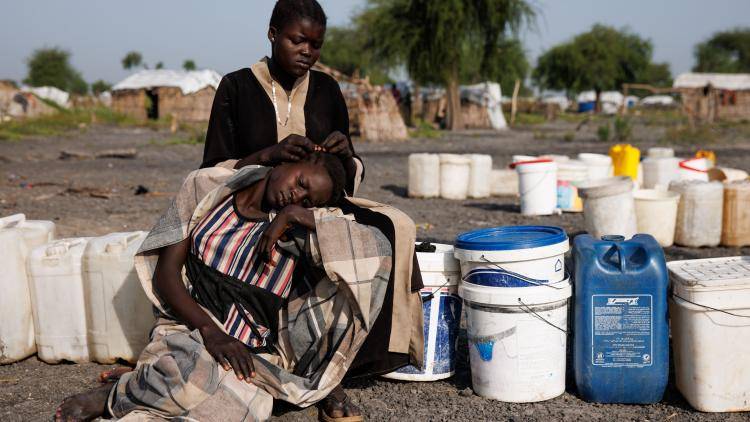 A young girl braids another's hair at a water pumping station in an Internally Displaced Persons (IDP) camp on November 29, 2023 in Rotriak, South Sudan