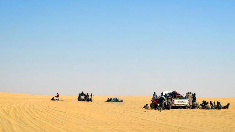 A group of migrant men, mainly from Niger and Nigeria, have a rest next to pick up vehicles, during a journey across the Air dessert, northern Niger. 