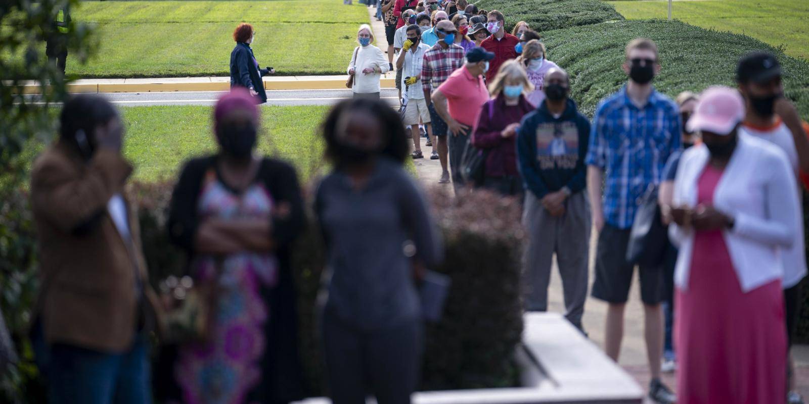 Voters in protective masks wait in line to cast early ballots for US 2020 elections