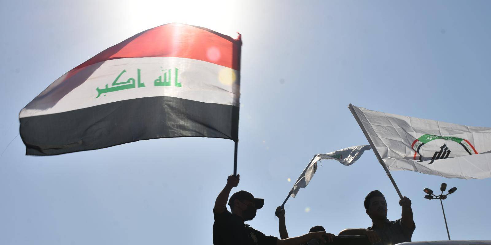 protestors holding flags of Iraq and the PMF
