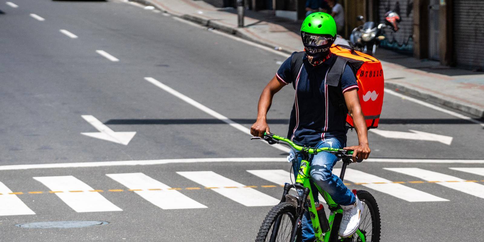 Photo of a delivery courier wearing a protective mask riding through Medellin, Colombia.