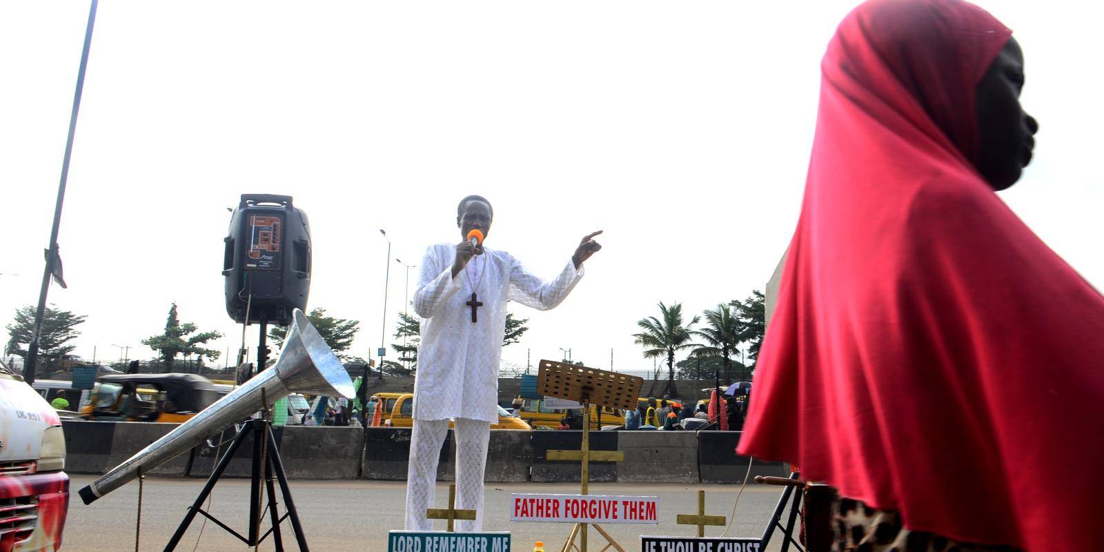 Muslim girl walks past Christian preacher in Nigeria.