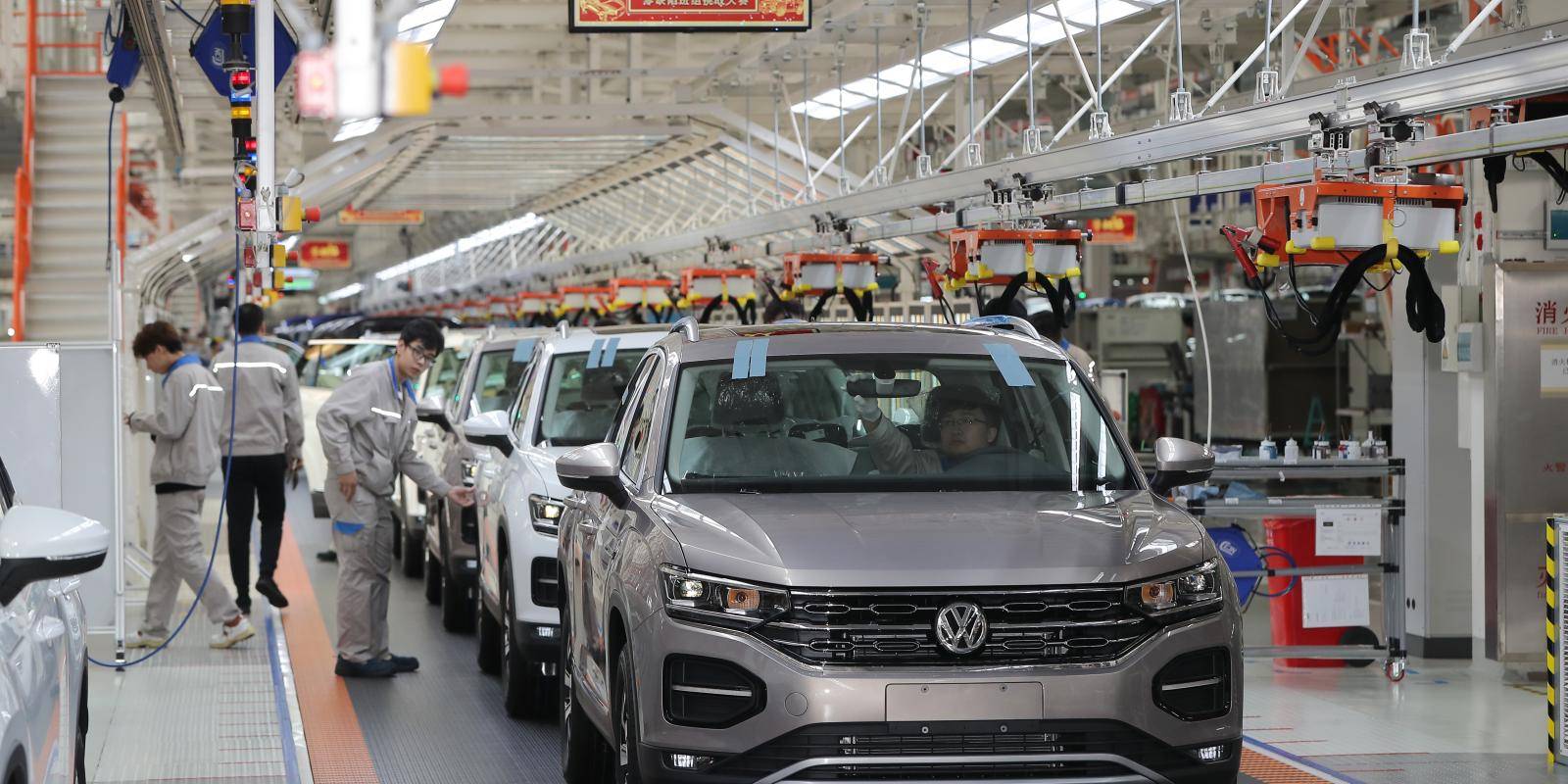 Image shows workers and vehicles at a VW assembly line in Tianjin, China
