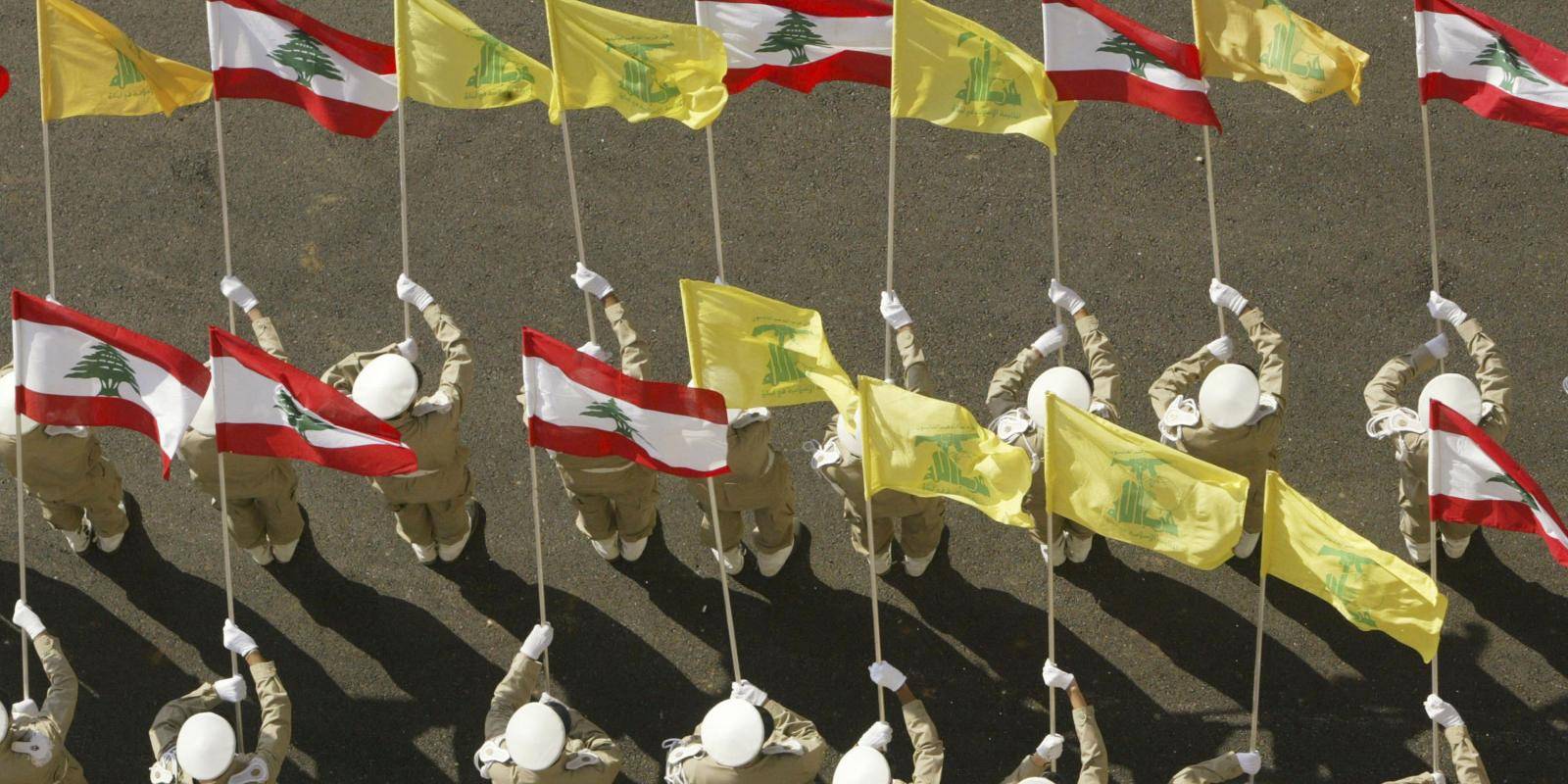 Hezbollah members in uniform form an honour guard holding Lebanese and Hezbollah flags in Beirut