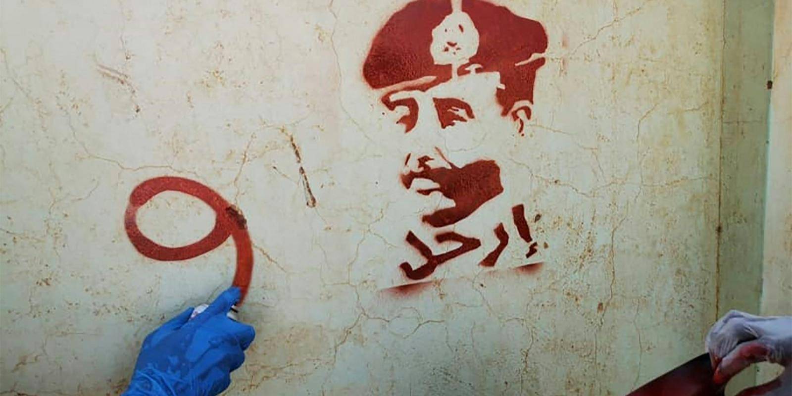 Spraying next to a stencil painting of Sudan's top army general Abdel Fattah al-Burhan with a writing in Arabic that reads 'leave' during a protest in Khartoum against the 2021 military coup. Photo by AFP via Getty Images.