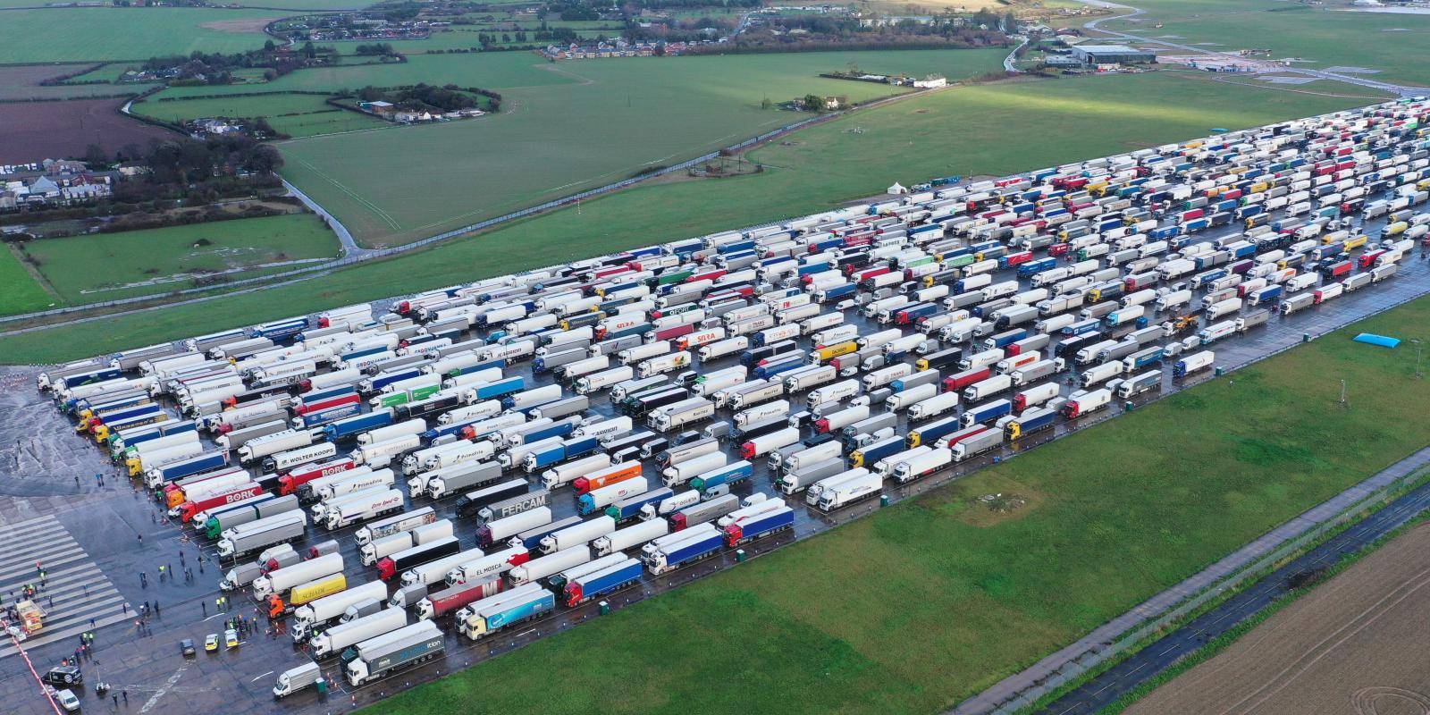 Aerial view of an airfield surrounded by open countryside and stacked with hundreds of parked lorries