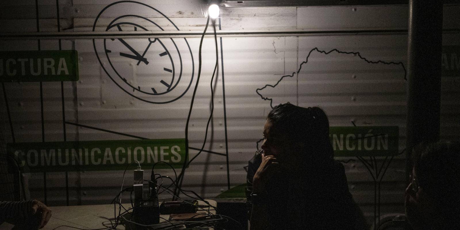 A woman in a dark room where a generator is providing power and dim light