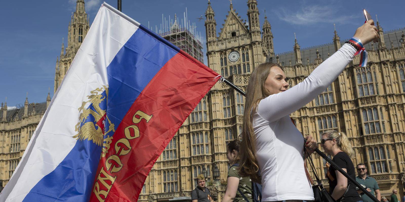A woman carrying a Russian flag parades in front of the Palace of Westminster