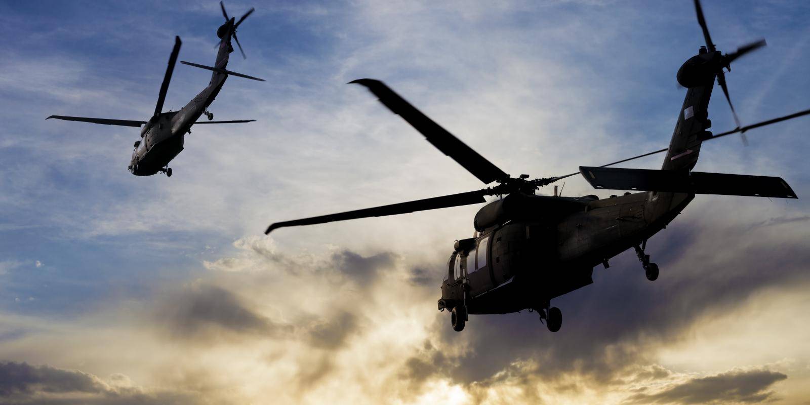Military helicopters flying into the sunset.
