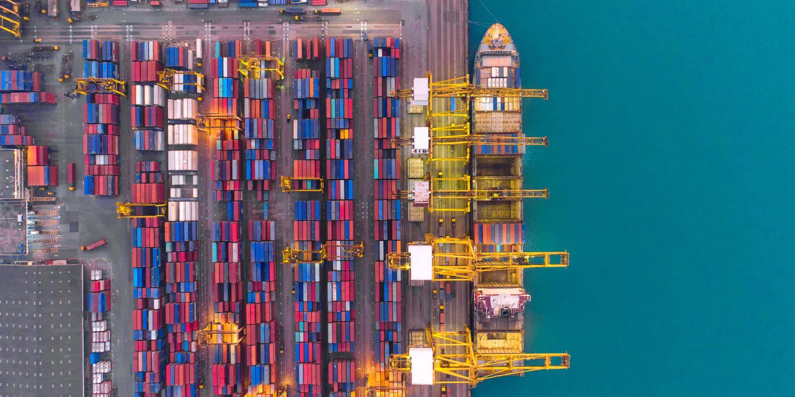 Cargo ship being loaded with containers at a dock.