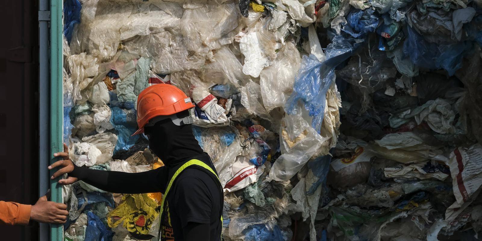 Two operatives open a container filled with plastic waste