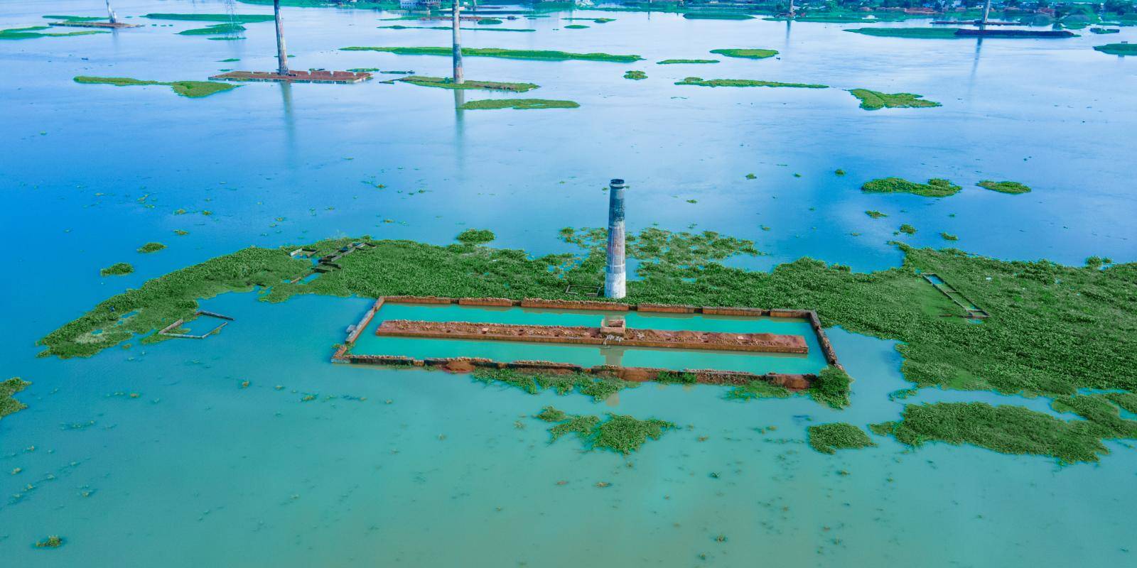 Extensive flooding surrounds the outline of a building and a tall chimney.