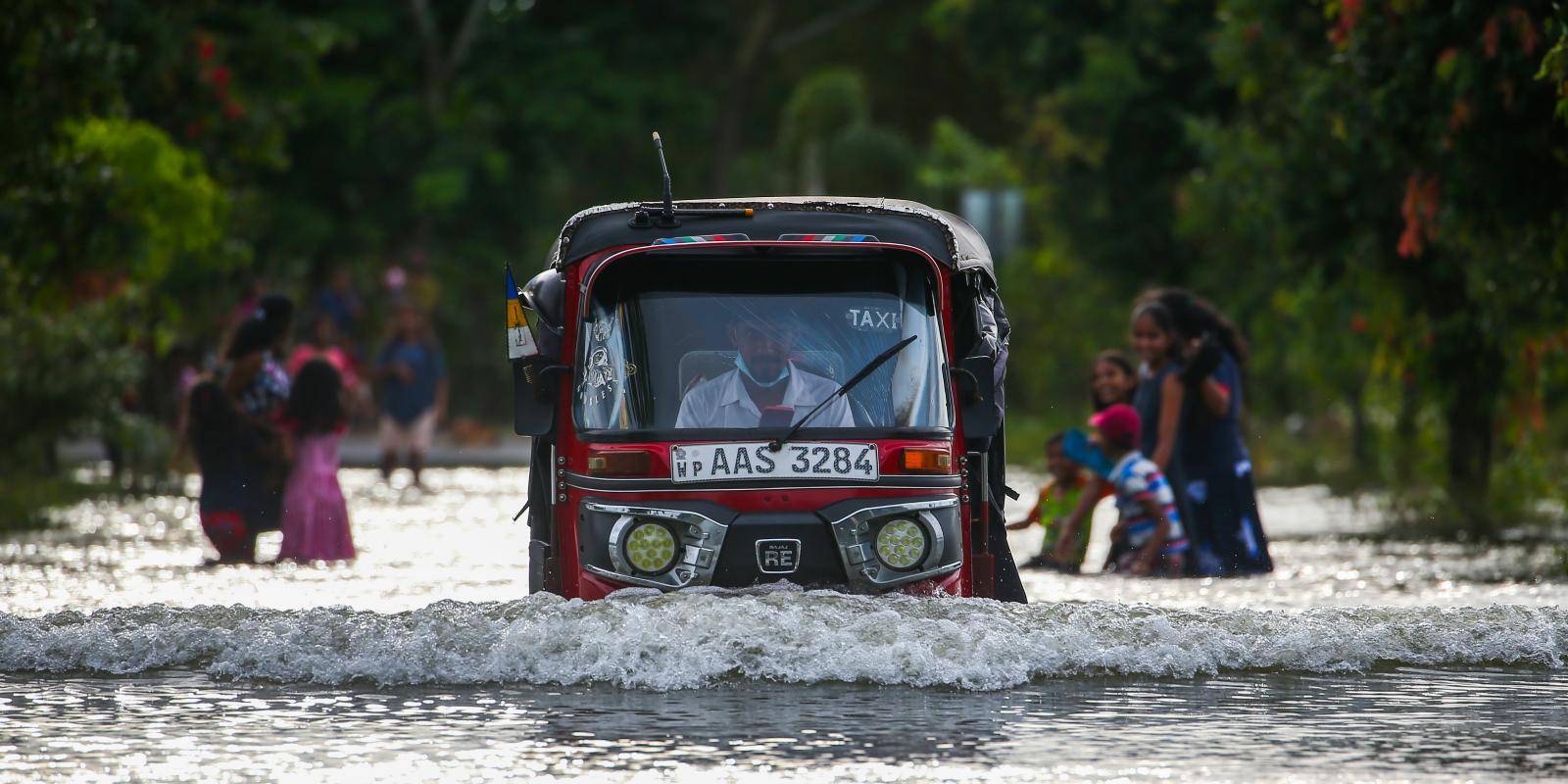 Photo of a tuk-tuk driving through a flooded street near the Sri Lankan capital, Colombo, in 2022.