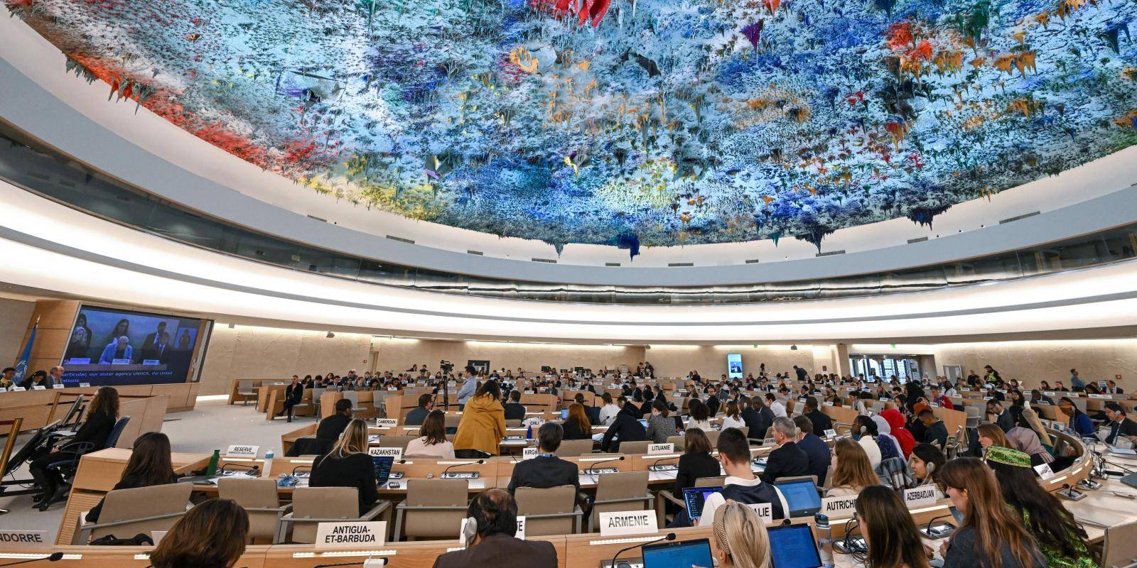 Delegates sit at desks under the multicoloured and textured ceiling of the Human Rights and Alliance of Civilizations room at the UN headquarters in Geneva, Switzerland.