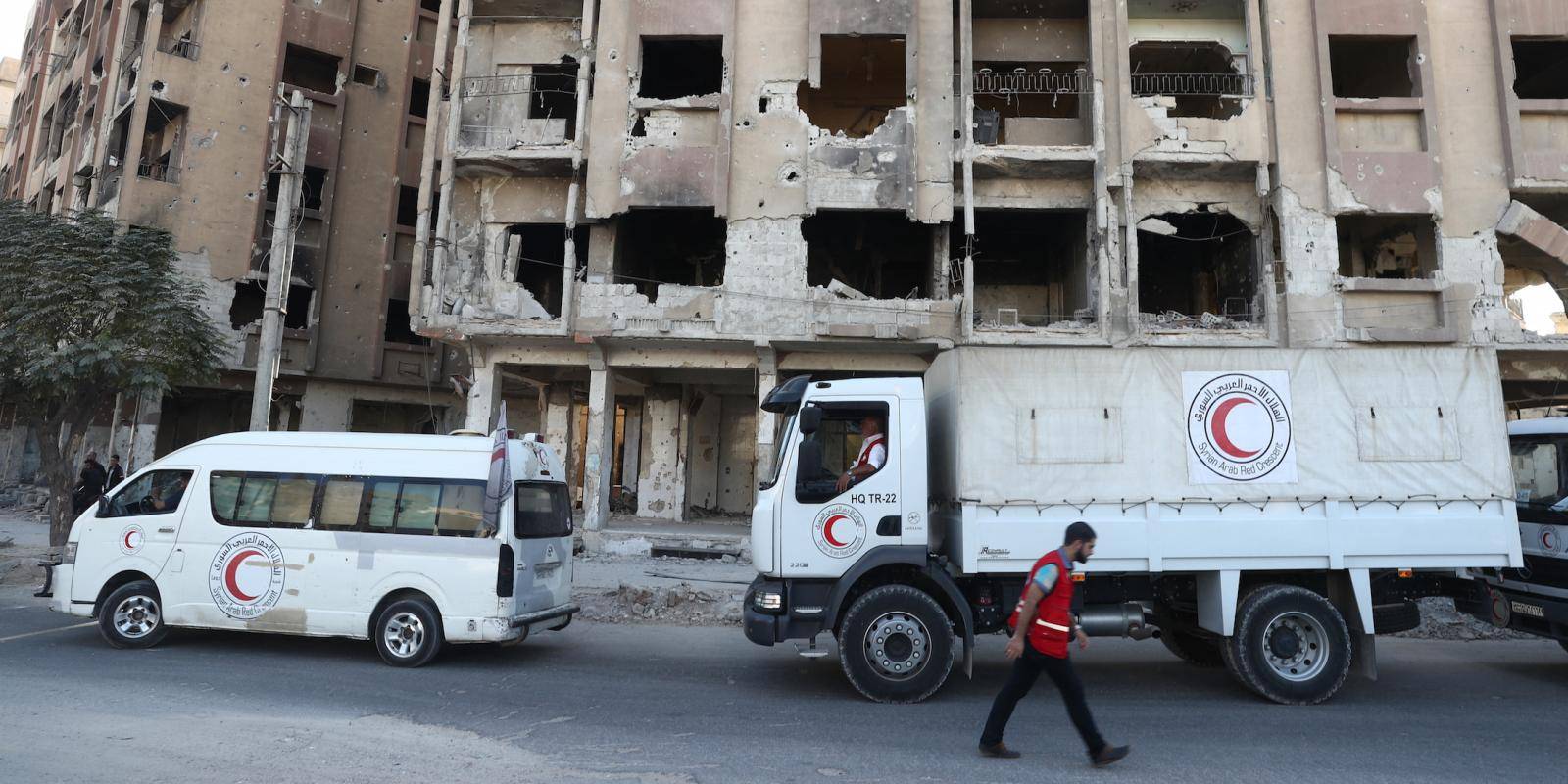 Red Crescent aid trucks drive through war-torn Syrian street