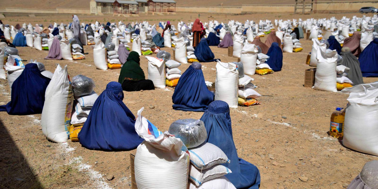 Women in Afghanistan sit next to food aid