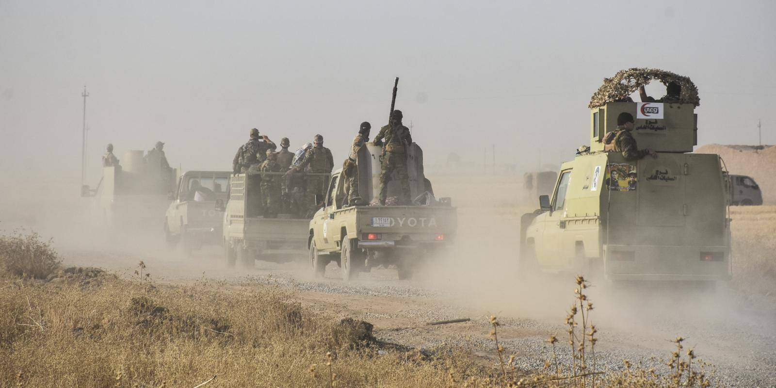 A convoy of armoured vehicles carries Iraqi troops along a dusty road during operations against Islamic State.