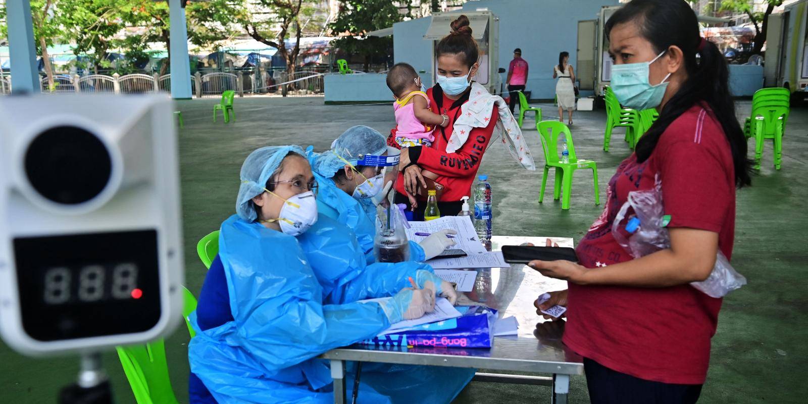 Women health workers and members of the public at a COVID-19 test station in a sports stadium in Bangkok