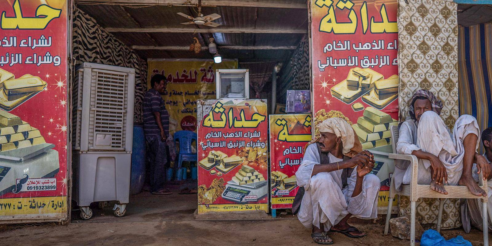 Men sit outside a gold-trading business in Sudan.