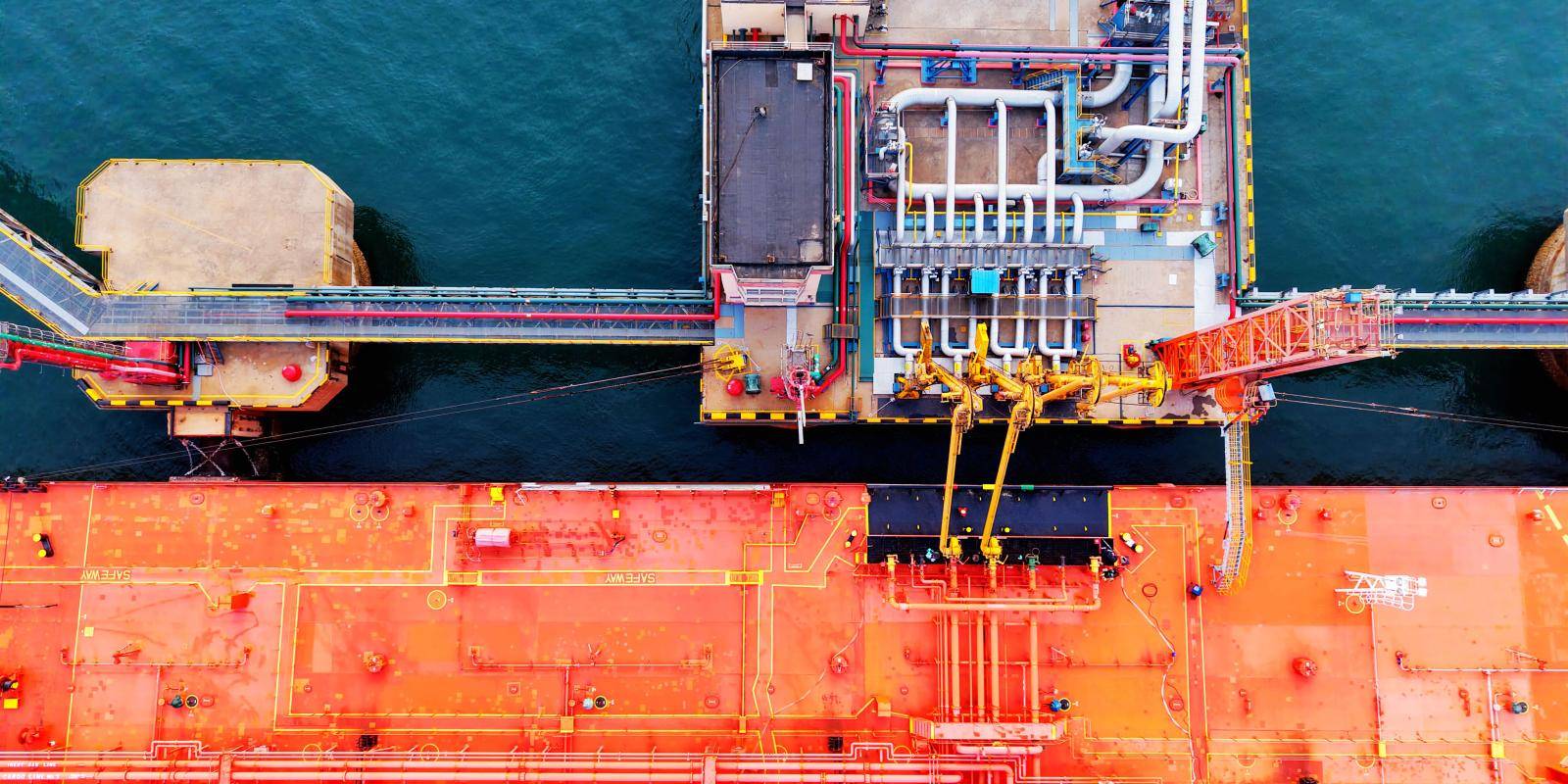An overhead view of an oil tanker unloading its cargo in port.