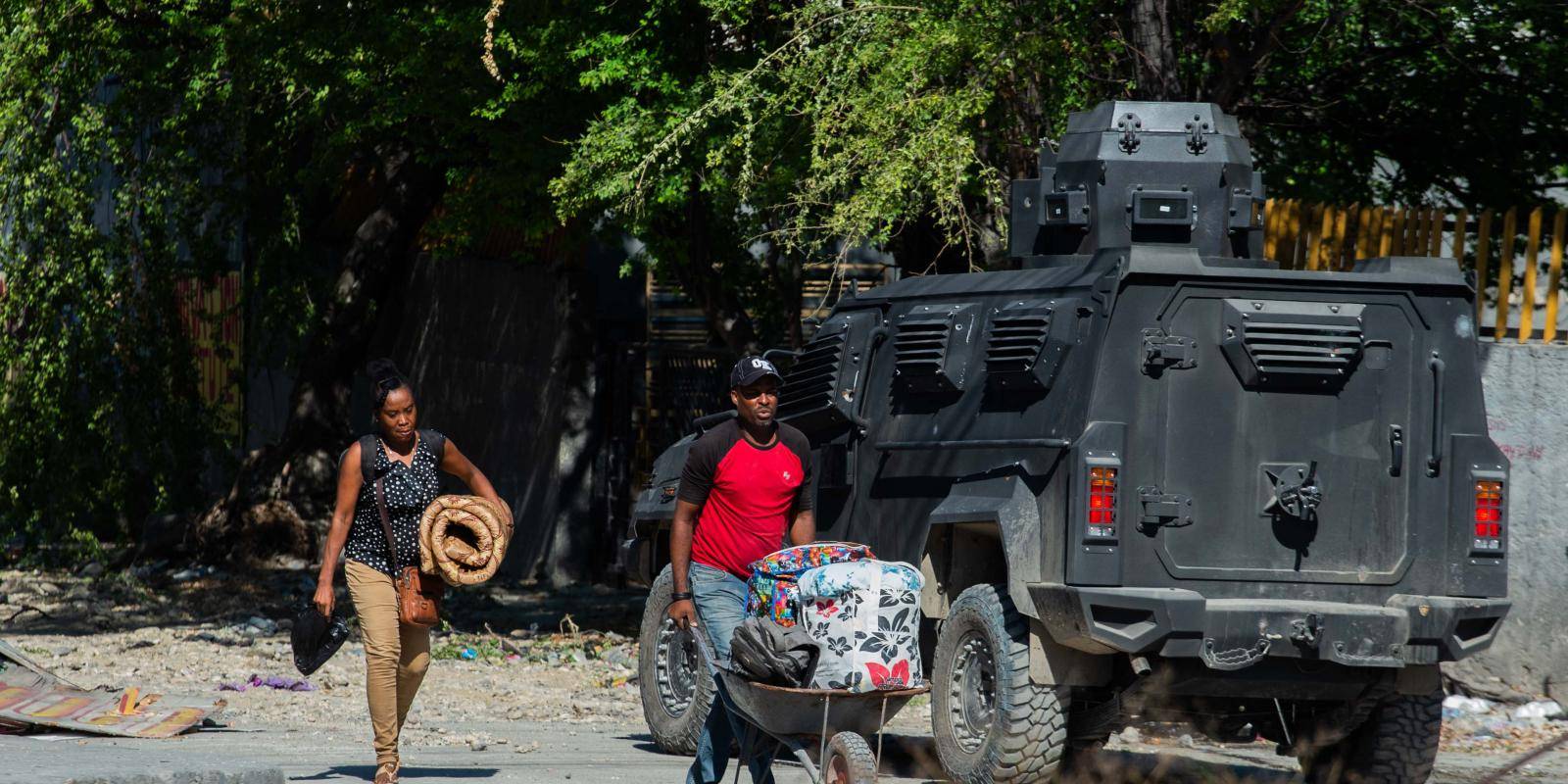 Residents walk past a police patrol around Bernard Mevs hospital in Port-au-Prince, December 2024.