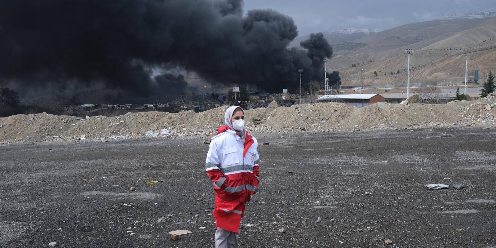 Photo of woman standing in front of plume of smoke from air strike