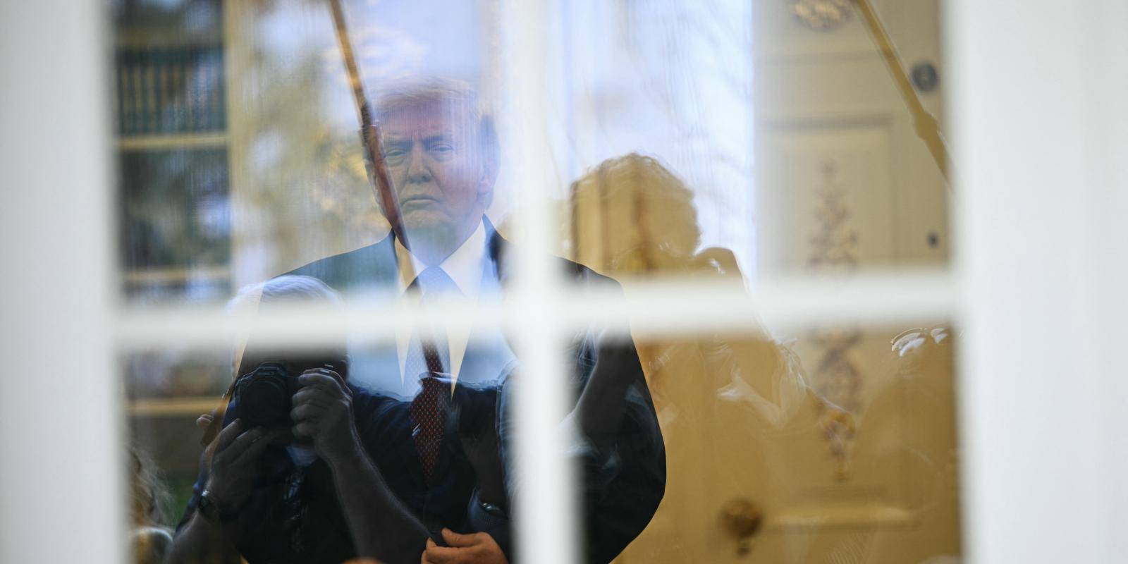 Photo of President Trump standing behind a window