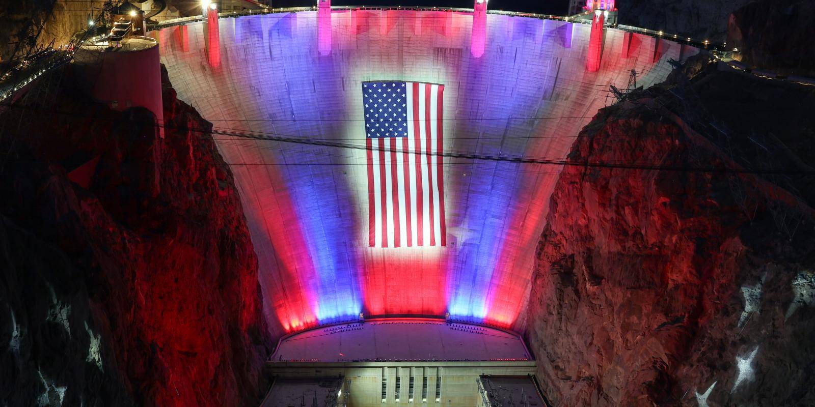 Image of the Hoover Dam with an American flag and patriotic lighting.