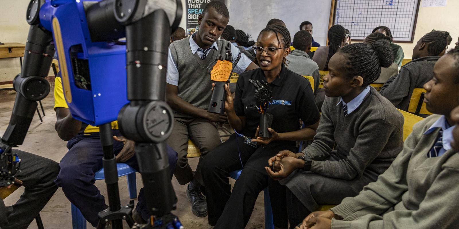 Photo of school children engaging with a robotic arm