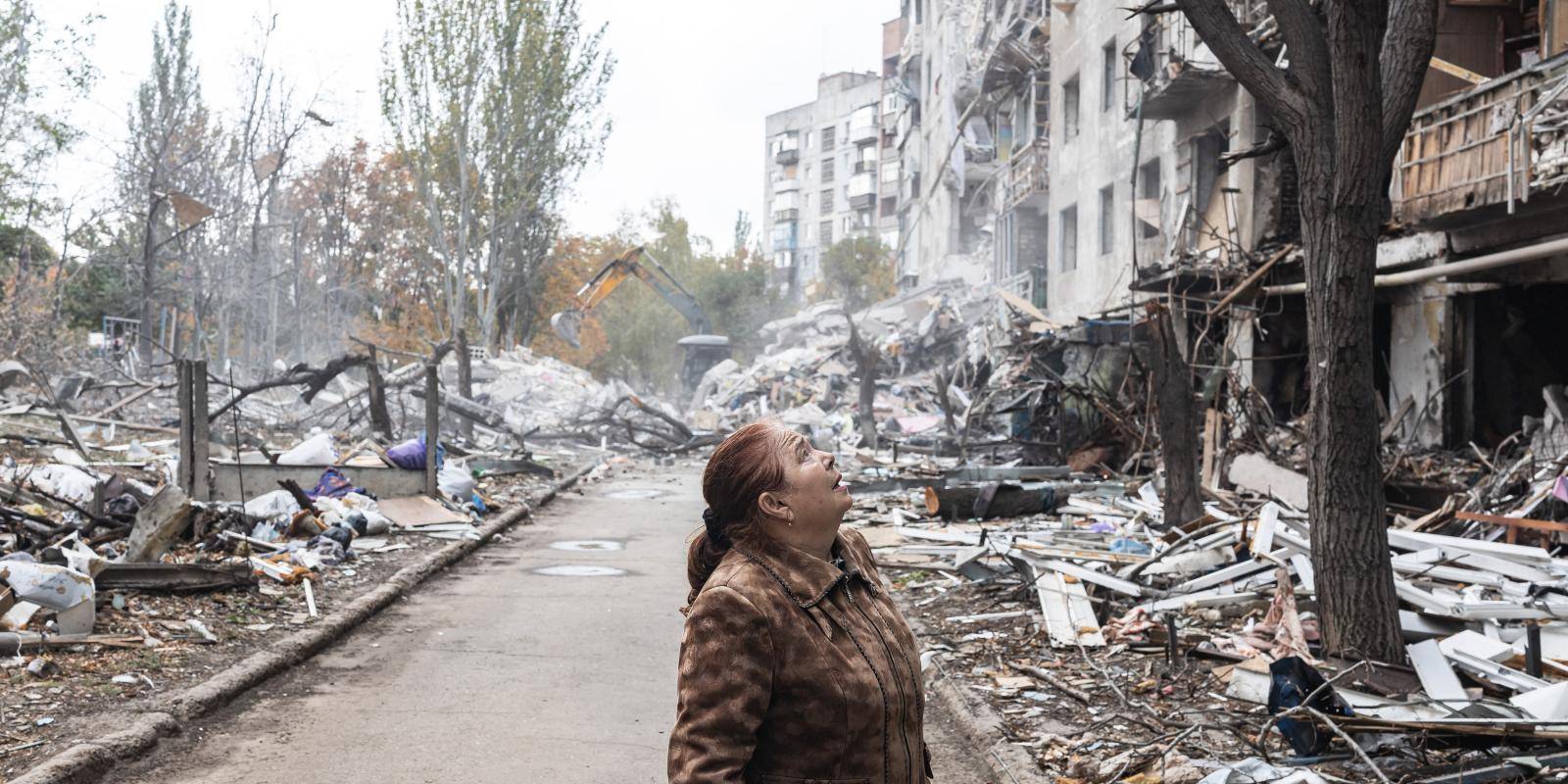 Woman looks up at buildings destroyed by Russian strike in Ukraine