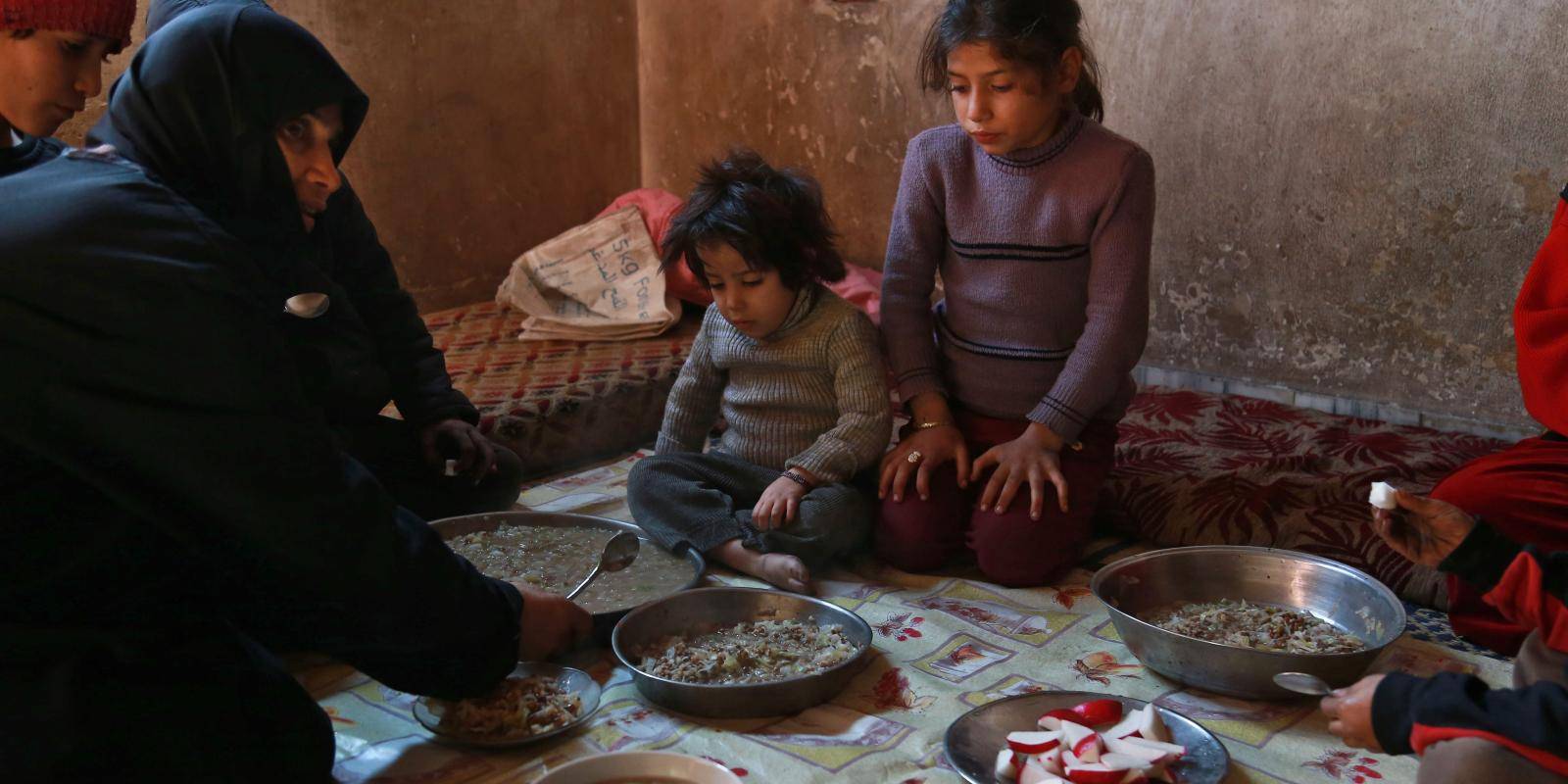 A Syrian family gather to eat a plate of corn and cabbage in Saqba, in the besieged rebel-held Eastern Ghouta area near Damascus on 6 November 2017. Photo: Getty Images