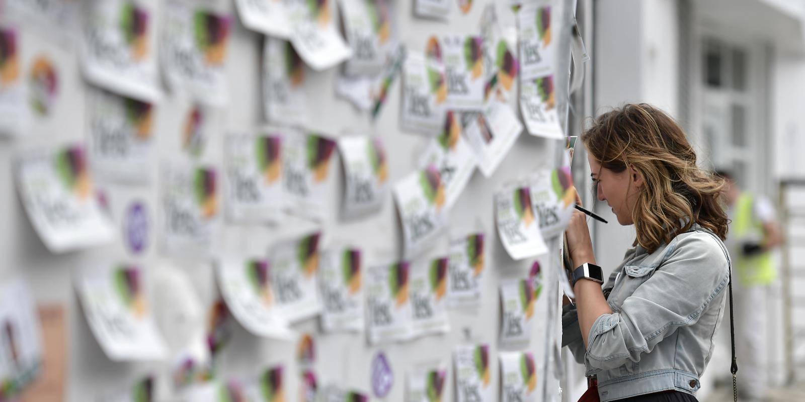 A woman writes a note on the Savita Halappanavar mural in Dublin on 26 May 2018, following a referendum on the 36th amendment to Ireland’s constitution. The referendum result was overwhelmingly in favour of removing the country’s previous near-universal ban on abortion. Photo: Getty Images.