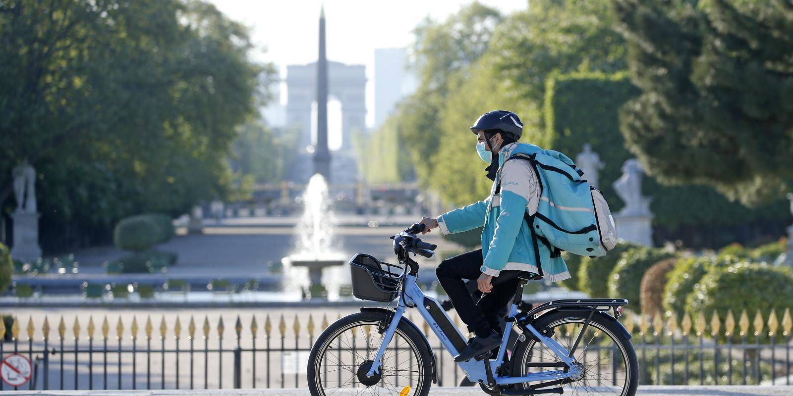 A Deliveroo rider wearing a protective mask rides his bike in the Jardin des Tuileries, Paris, 15 April 2020. Photo: © Chesnot/Getty Images