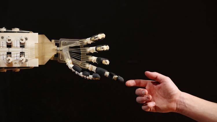 Robotics student Gildo Andreoni interacts with a Dexmart robotic hand built at the University of Bologna. Photo by Oli Scarff/Getty Images.