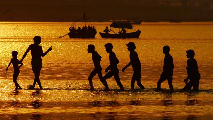 Indian Hindu devotees silhouetted as they take a holy dip at the Sangam - the confluence of rivers Ganges, Yamuna and mythical Saraswati. Photo by Sanjay Kanojia/AFP via Getty Images.