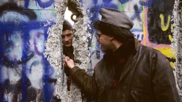 Shaking hands through the Berlin Wall.