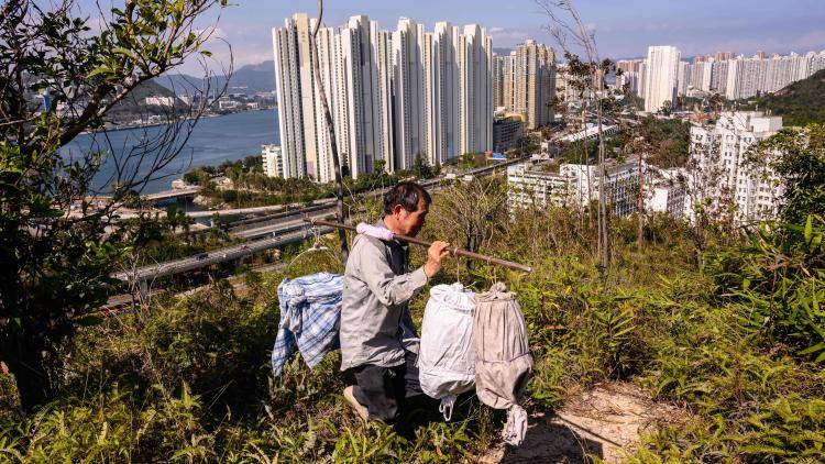 A Beekeeper walking in the hills of Hong Kong with skyscrapers behind