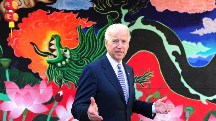 Picture of Joe Biden standing in front of a dragon wall-mural