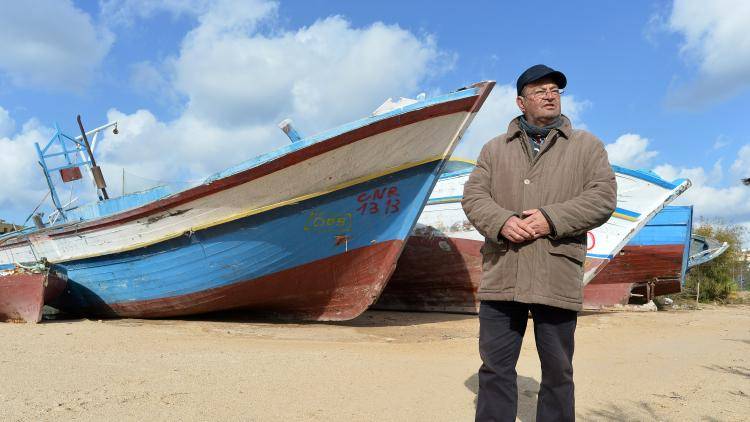 A man stands next to a migrant boat