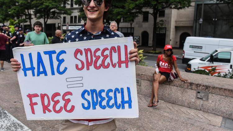 A person holding a placard that says: 'Hate speech = Free speech'