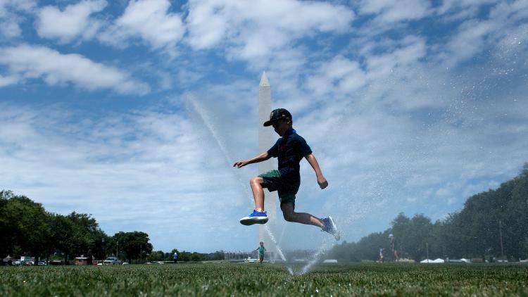 A child plays in front of the Washington National Mall during a heatwave