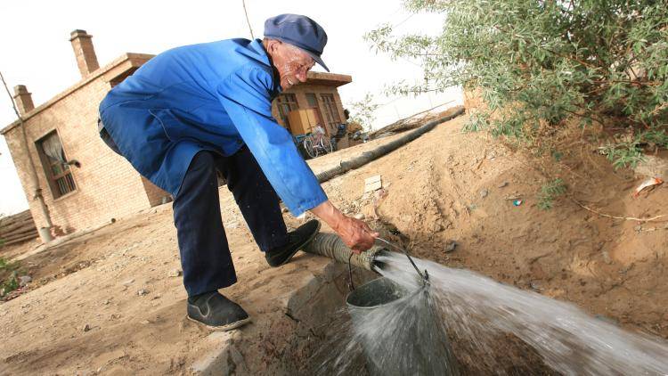 A farmer getting water from a well in a desert in China
