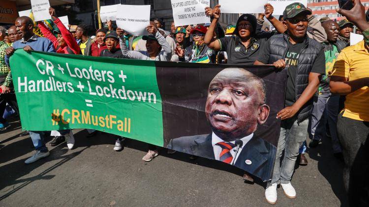 Disgruntled members of the ruling African National Congress (ANC) march holding a poster reflecting the face of South African President Cyril Ramaphosa.