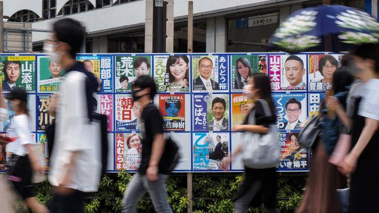 People walk past campaign posters for Japan's upper house election in Tokyo on July 10, 2022.