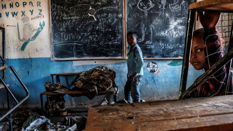 Children look on in an abandoned classroom in Tigray