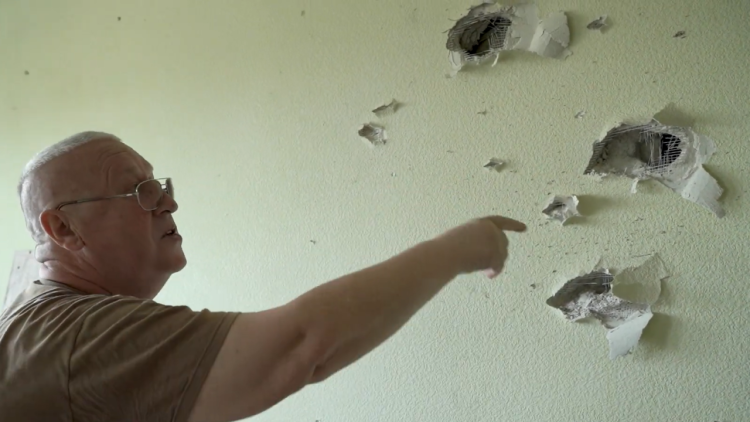 A resident of Bucha points to war damage in his home