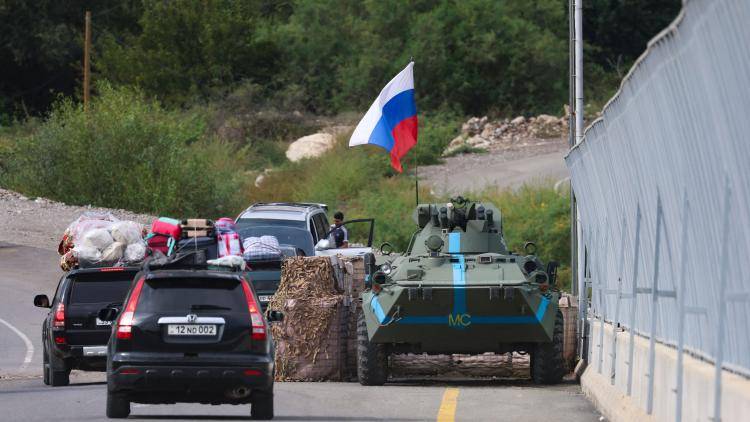 Cars passes next to a Russian peacekeeper vehicle, as they leave Karabakh to Armenia