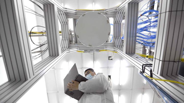 A man with a laptop stands inside a quantum computing lab at Beijing Academy of Quantum Information Sciences 