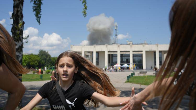 A child and a woman flee an explosion caused by a missile strike behind the Palace of Culture in Pervomaiskyi, Ukraine, 4 July 2023